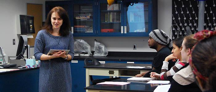 Students in a science lab look to their professor for classroom instruction.