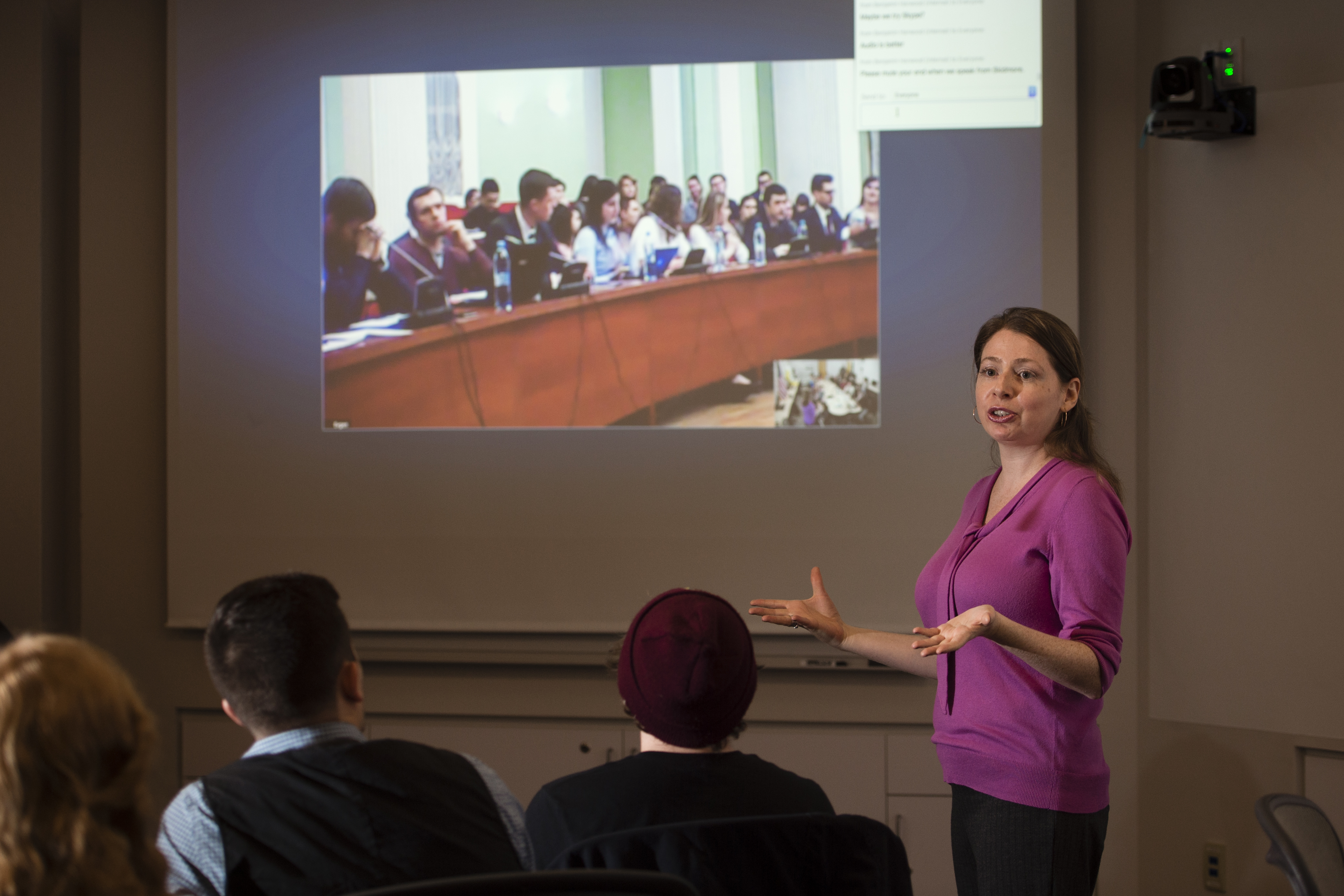 Students in the LEDS space interact with a panel of speakers over video-communication while the professor mediates.