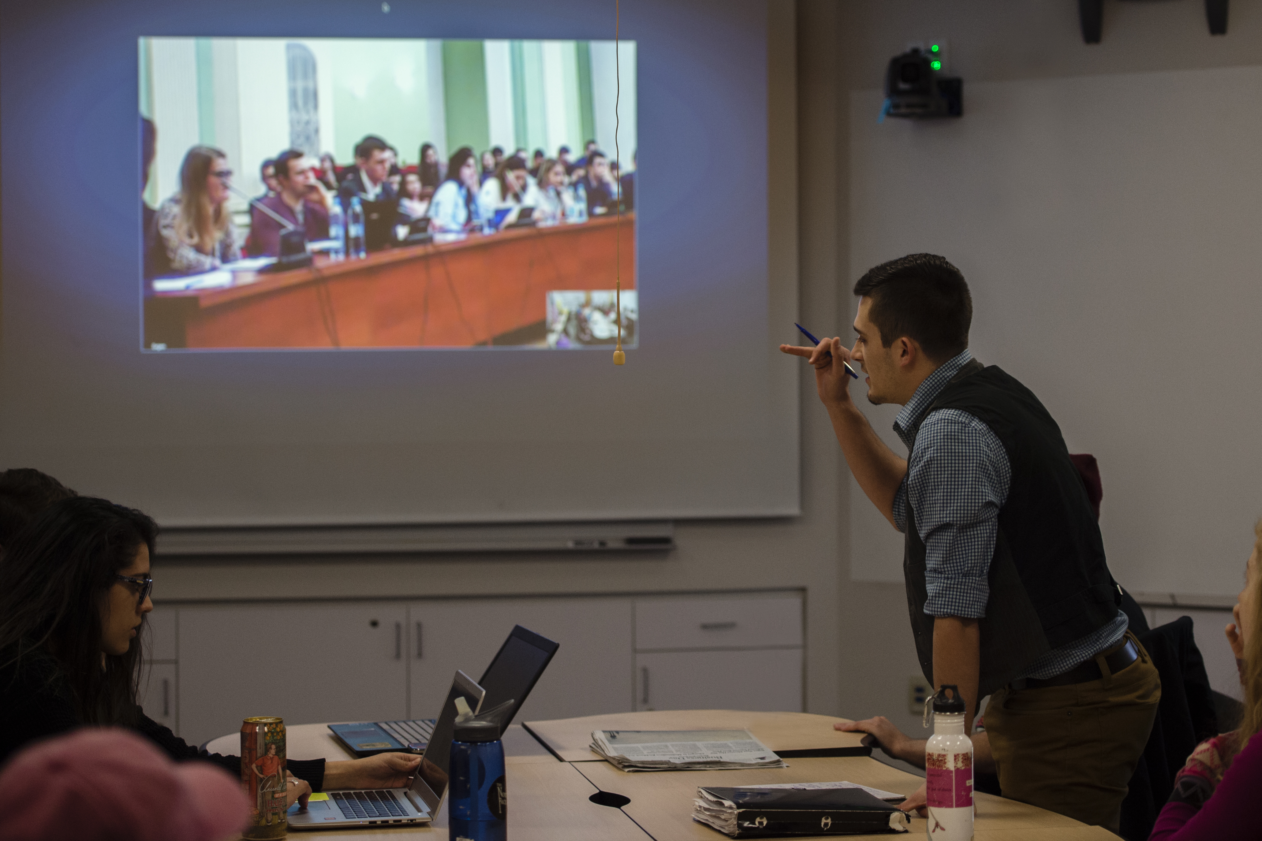 A student poses a question to a panel of speakers, connected remotely via video-communication.