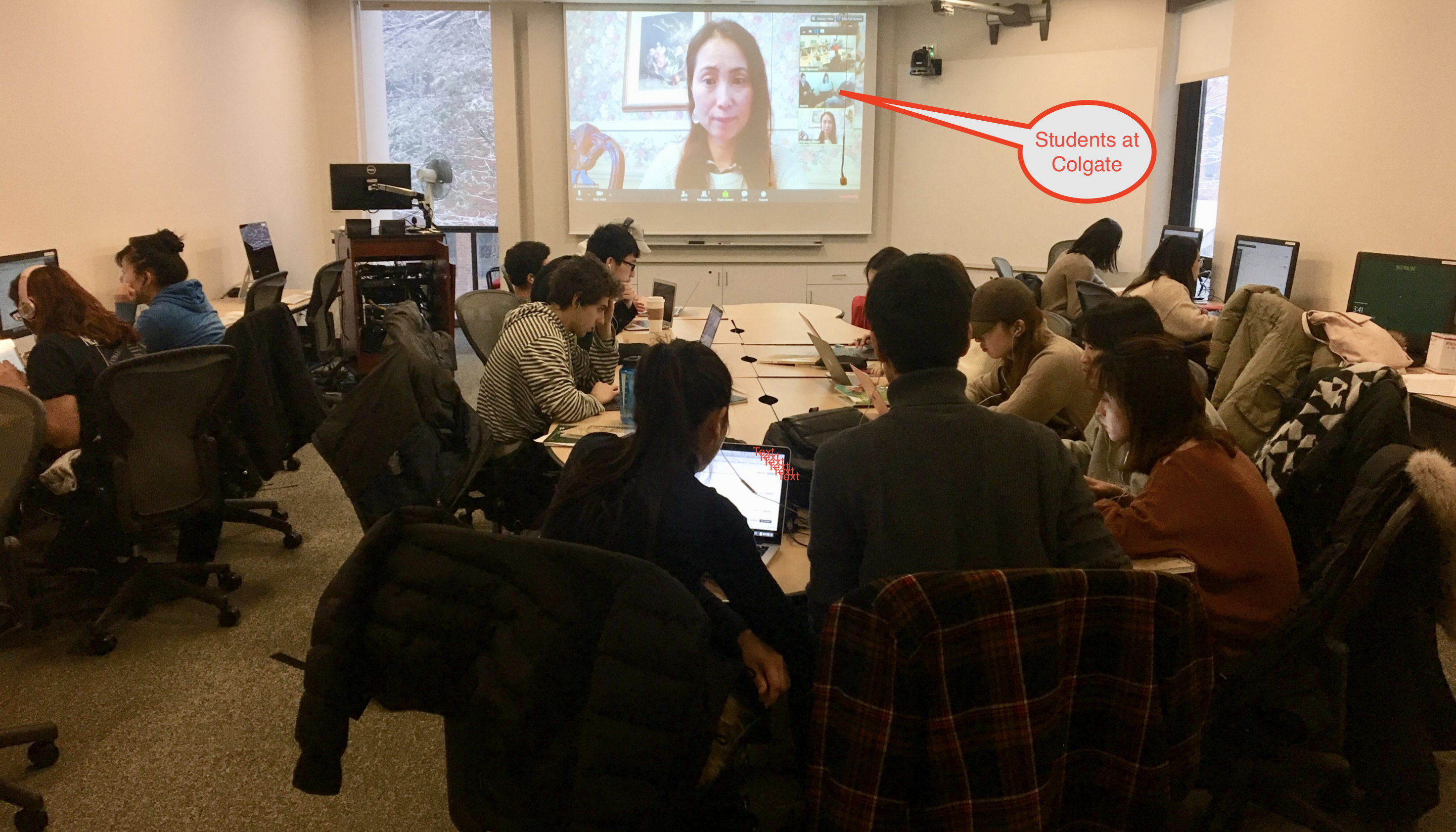 A group of students interacts over video-communication with students at Colgate University in real time.